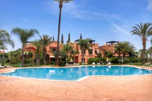 a large swimming pool in front of a building with palm trees at Duplex Atlas Golf Resort Pοοl νieω Seriniτყ & Cαlm in Marrakesh