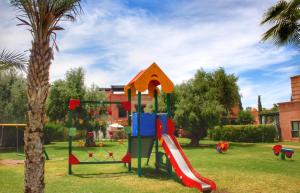 a playground with a slide in a park with a palm tree at Duplex Atlas Golf Resort Pοοl νieω Seriniτყ & Cαlm in Marrakesh +34 photos