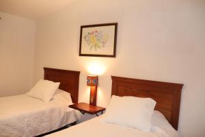 a bedroom with two beds and a picture on the wall at Casa Gabriel in Cusco