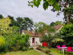 una casa bianca con sedie rosa e tavolo di Charmante maison avec jardin en face du parc, proche commerces et attractions touristiques - FR-1-489-333 a Moulins