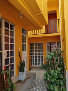 ein gelbes Haus mit Balkon und einigen Pflanzen in der Unterkunft Recámara rústica in Mexiko-Stadt