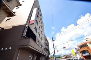 a tall building on a city street with a traffic light at New Station Hotel in Isahaya