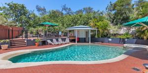 a swimming pool with chairs and umbrellas in a yard at Whale Watch Ocean Beach Resort in Point Lookout