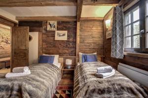 two beds in a room with wooden walls at Chalet Heron in Les Houches