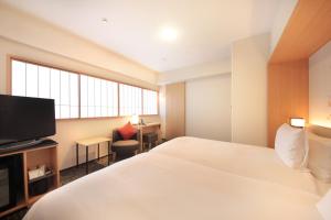 a hotel room with a bed and a flat screen tv at Richmond Hotel Premier Kyoto Ekimae in Kyoto