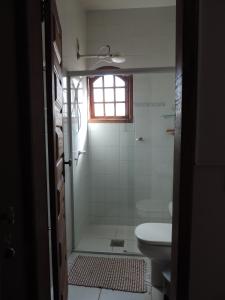 um banheiro com chuveiro, vaso sanitário e janela em Pousada Elisa em Tiradentes