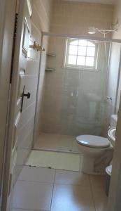 um banheiro com chuveiro, vaso sanitário e janela em Pousada Elisa em Tiradentes mais 16 fotografias