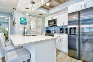 a kitchen with white cabinets and a stainless steel refrigerator at Water View 107 in Clearwater Beach