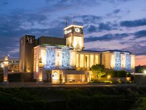 un gran edificio con una torre de reloj por la noche en Hotel QT Senboku (Adult Only) en Sakai