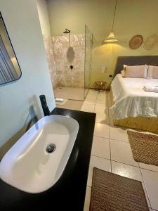 a bathroom with a white sink and a bed at Hotel y Cabinas del Trópico in Guápiles