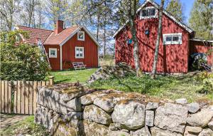 a red barn and a house with a stone wall at Three-Bedroom Holiday Home In Brakne Hoby in Bräkne-Hoby