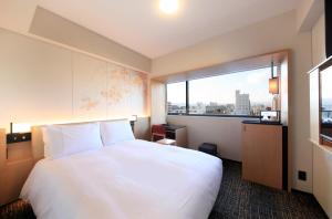 京都市にあるリッチモンドホテルプレミア京都駅前の白い大型ベッド1台と窓が備わるホテルルームです。
