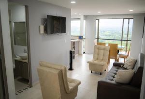 a living room with a couch and chairs and a kitchen at Apartamento con hermosa vista a 5 minutos del parque del café in Montenegro