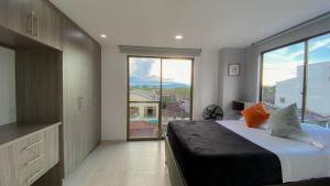 a bedroom with a large bed and a large window at Apartamento con hermosa vista a 5 minutos del parque del café in Montenegro