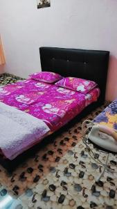 a bed with a purple comforter and a floor at HOMESTAY UMI KODIANG in Kodiang
