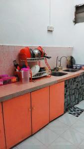 a kitchen counter with a dish drying rack and a sink at HOMESTAY UMI KODIANG in Kodiang