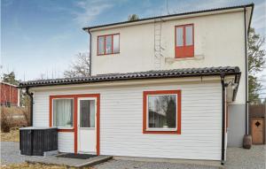 a white house with red windows and a garage at Stunning Apartment In Hlleforsns With Wifi And 2 Bedrooms in Hälleforsnäs