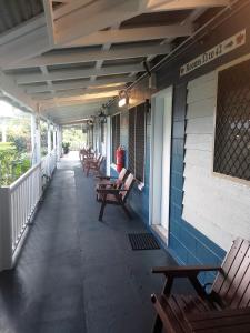 eine Reihe von Bänken auf der Veranda eines Gebäudes in der Unterkunft Cooktown Motel in Cooktown