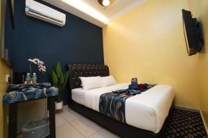 um quarto com uma cama e uma televisão e uma roupa de cama. em Ghazrin's Classic em Johor Bahru