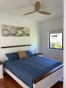 Schlafzimmer mit einem blauen Bett und einem Deckenventilator in der Unterkunft The Norfolk in Smiths Lake