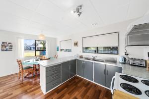 a kitchen with a sink and a stove top oven at Babbacombe Bach - Otaki Beach Holiday Home in Otaki Beach