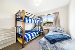 a bedroom with two bunk beds and a window at Babbacombe Bach - Otaki Beach Holiday Home in Otaki Beach