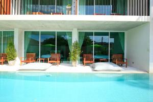 a swimming pool with chairs and tables and windows at Wabi Sabi Boutique Hotel - SHA Extra Plus in Kamala Beach