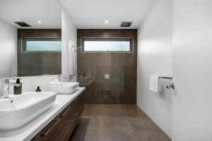 a white bathroom with two sinks and a shower at Coastal Chic in Saint Andrews Beach +19 photos