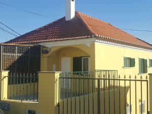 een geel huis met een hek en een kruis erop bij Hostel Zabava in Odivelas