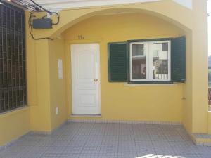 un bâtiment jaune avec une porte blanche et une fenêtre dans l'établissement Hostel Zabava, à Odivelas
