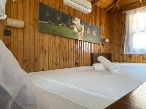 a bedroom with a white bed with a wooden wall at Olympos Route 66 Pansiyon in Olympos