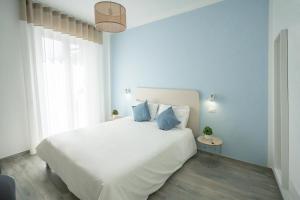 uma cama branca com almofadas azuis num quarto em Dimora del Corso - Rooms em Mattinata
