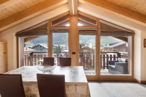 a dining room with a table and a large window at Baita Nicoletta Dream Attic in Livigno