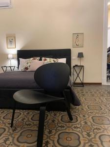 ein Schlafzimmer mit einem Bett und einem schwarzen Stuhl in der Unterkunft Lex Suites in Catania
