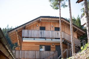 a wooden house with a balcony and trees at Apartment MOUNTAIN PEARL Golte in Mozirje