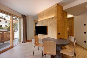 una sala da pranzo con tavolo, sedie e TV di Wind Mountain Planet Suite House a Livigno