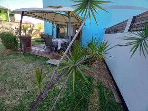 a house with a wooden deck with a table and an umbrella at Maison Job in Saint-Louis