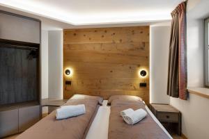 2 letti in una camera con parete in legno di Ice Mountain Planet Suite House a Livigno