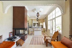 een woonkamer met een open haard en een keuken bij Villa du Cedre in Marrakesh