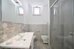 uma casa de banho branca com um lavatório e um WC em Dimora del Corso - Rooms em Mattinata