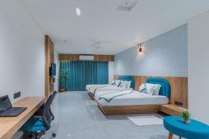 Habitación con 2 camas y escritorio con ordenador portátil. en Hotel The Grand Heaven en Gandhinagar