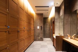 Via Inn Prime Hiroshima Shinkansenguchi في هيروشيما: غرفة خزانة مع خزائن خشبية في صالة ألعاب رياضية