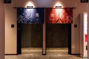 two banners on the wall of a building with chinese signs at Via Inn Prime Hiroshima Shinkansenguchi in Hiroshima