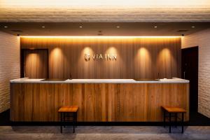 a lobby with a counter with two wooden benches at Via Inn Prime Hiroshima Shinkansenguchi in Hiroshima