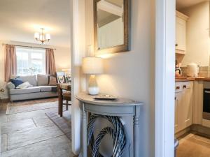 eine Küche und ein Wohnzimmer mit einem Tisch und einer Lampe in der Unterkunft Manor Barn Cottage in Bakewell