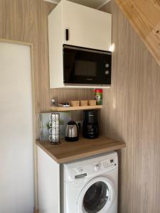 a kitchen with a washing machine and a microwave at Au fil de l’eau, gîte nature in Abbécourt