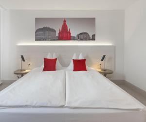 una camera da letto con un letto bianco con cuscini rossi di Ramada by Wyndham Dresden a Dresda