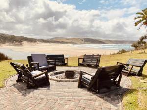 a group of chairs sitting around a fire pit next to a beach at Bulungula Xhosa Community Lodge in Bulungula