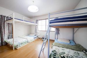 a bedroom with two bunk beds and a window at GUESTHOUSE CHIYOGAOKA in Asahikawa