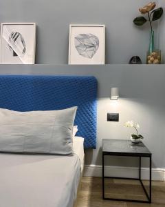 Schlafzimmer mit einem Bett mit blauem Kopfteil und einem Tisch in der Unterkunft Calumidda in Catania